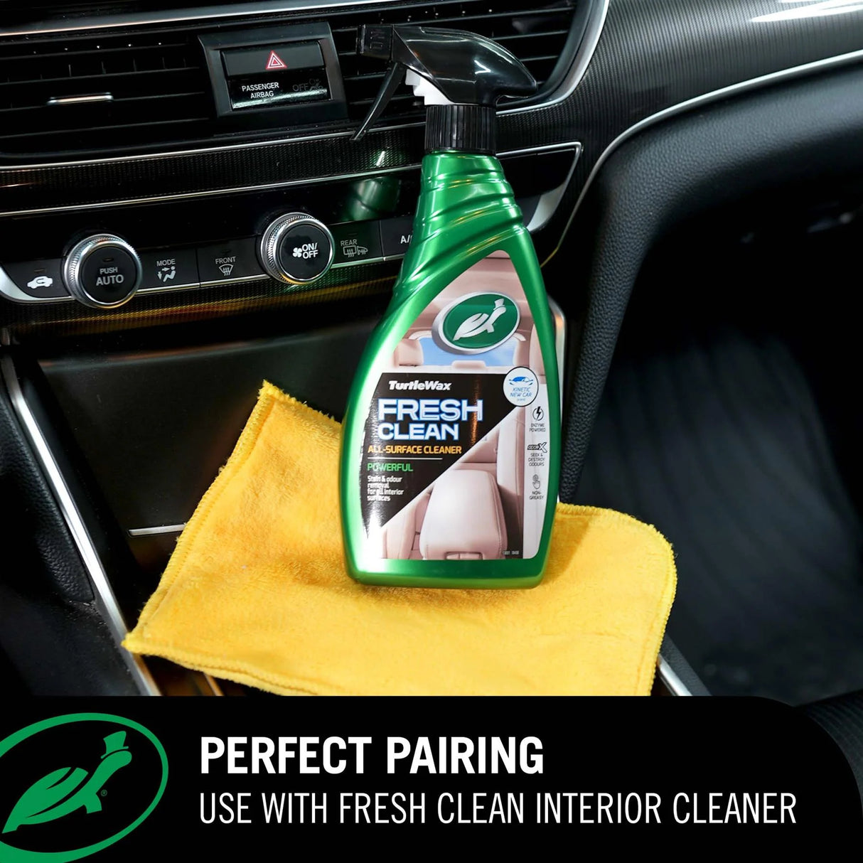 A bottle of Turtle Wax Fresh Clean car interior cleaner placed on a yellow microfiber cloth inside a car console. A black banner at the bottom reads 'PERFECT PAIRING USE WITH FRESH CLEAN INTERIOR CLEANER' with the Turtle Wax logo.