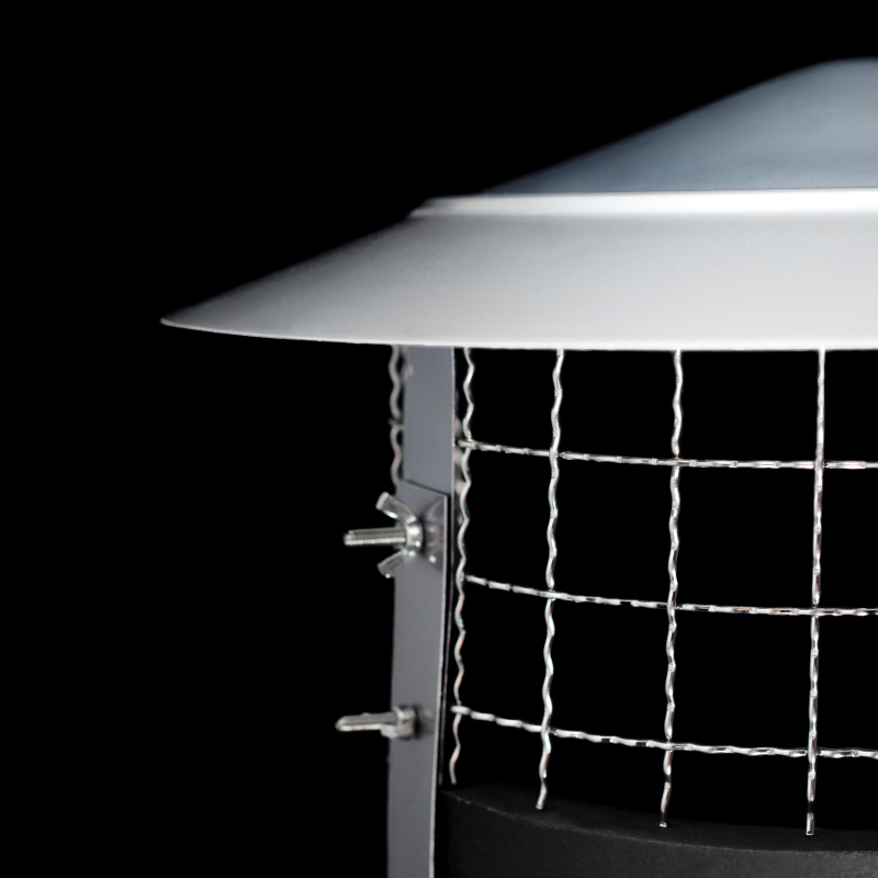 Close-up of a metal outdoor light fixture or vent cover with a wide white top section, silver wire mesh grid, and mounting hardware against a black background.