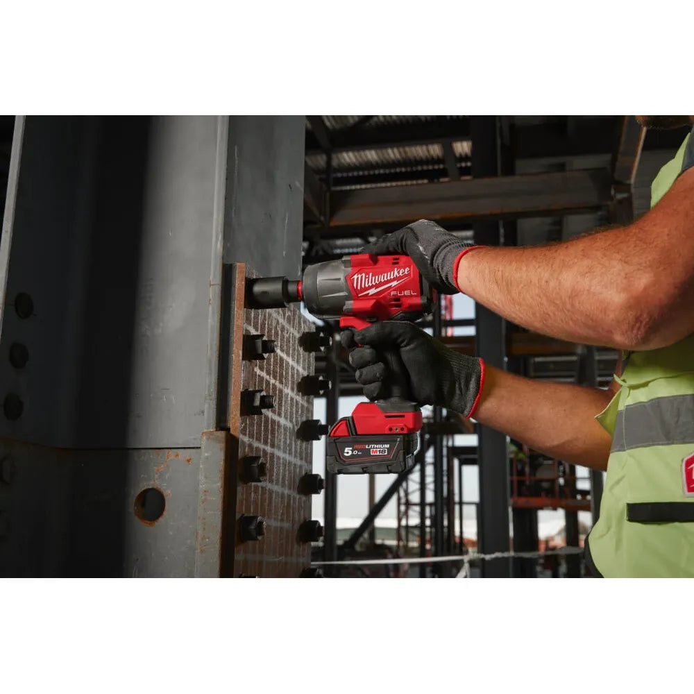 A worker wearing black gloves uses a red and black Milwaukee cordless impact wrench to tighten a bolt on a metal structure in an industrial setting.
Milwaukee M18 Fuel High Torque Impact Wrench With Friction Ring M18FHIW2F12-0