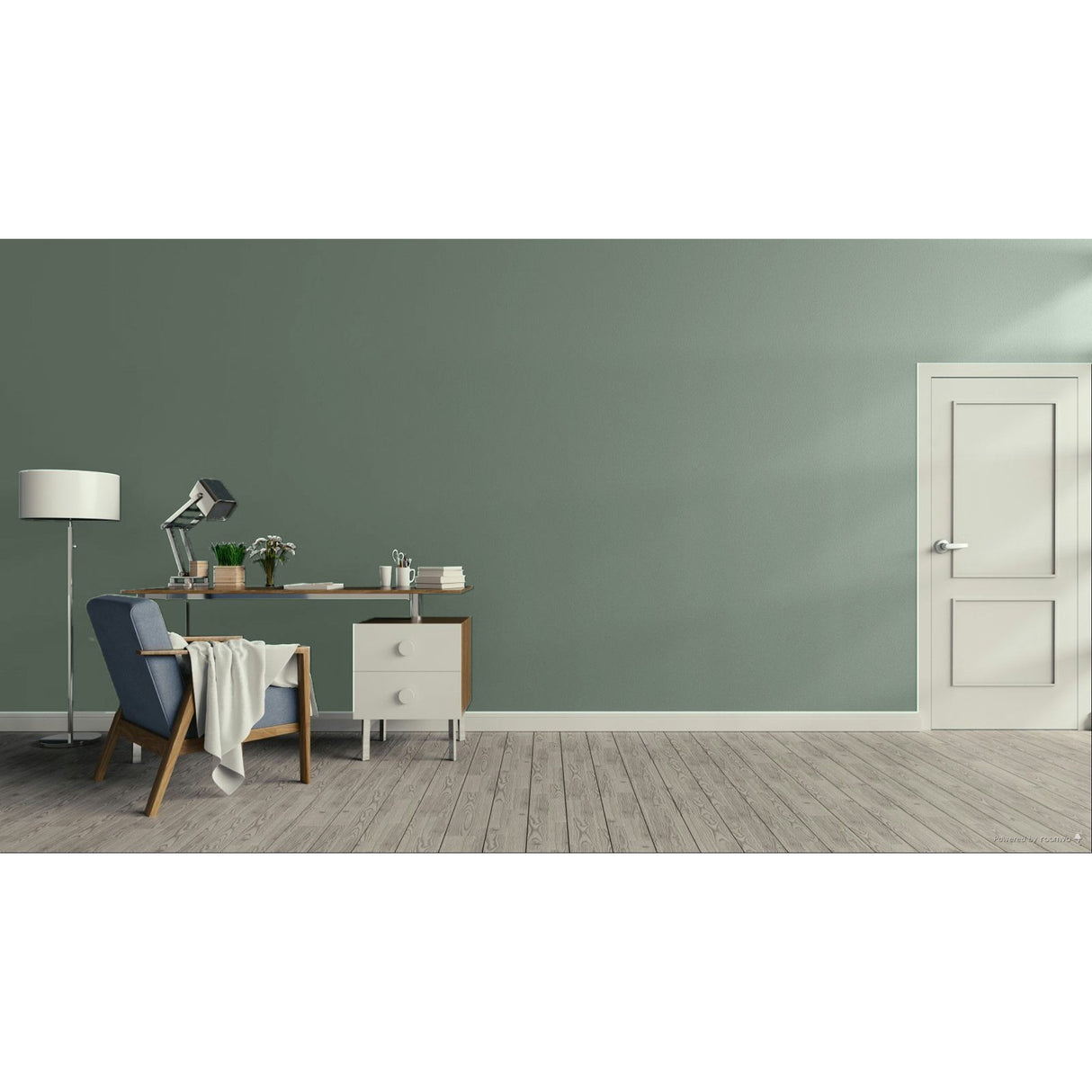 A styled interior room with a muted sage green wall, light wood floor, a white door on the right, and a home office setup on the left featuring a blue armchair, desk, lamp, and small cabinet.