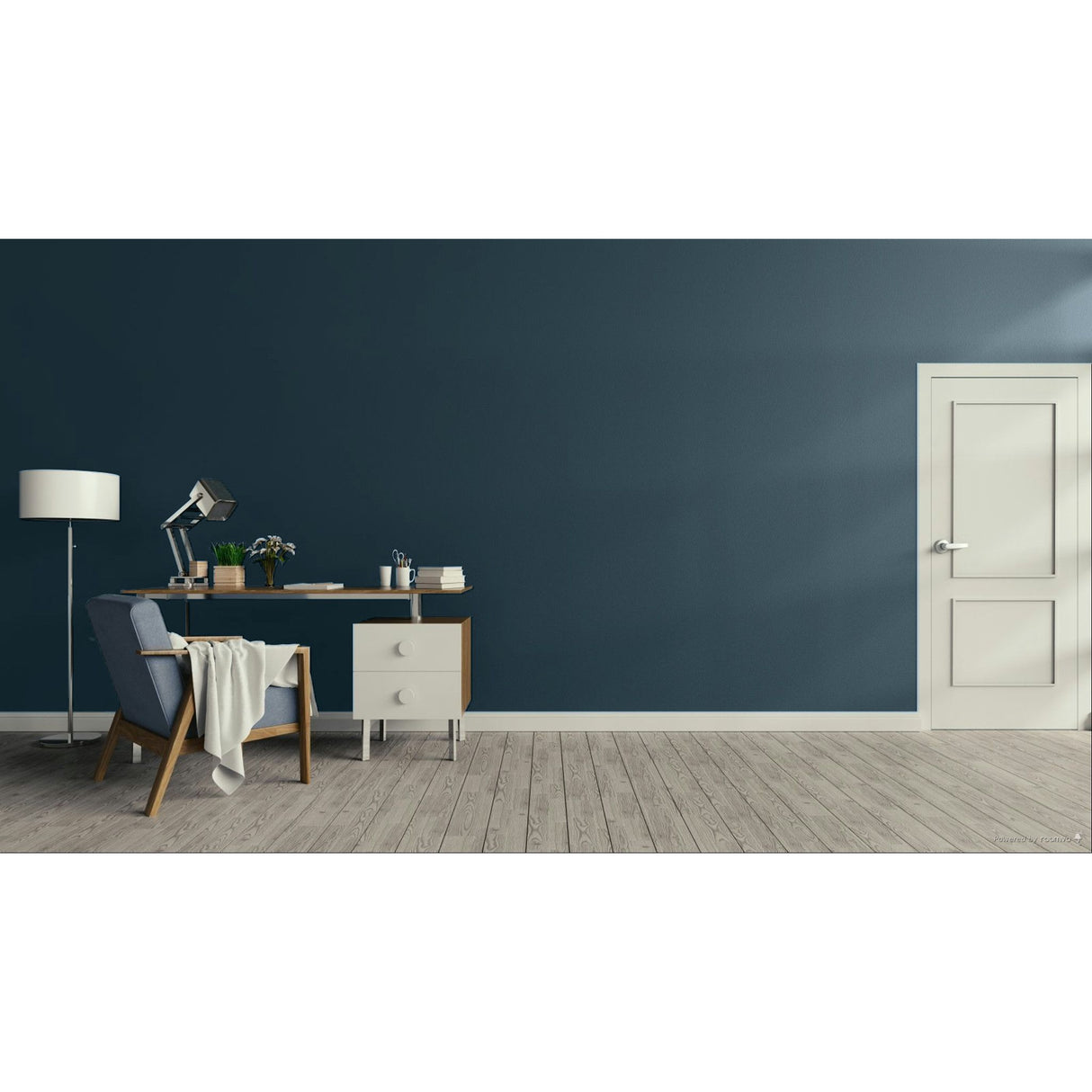 A modern interior room with a dark blue wall, light wood floor, a white door on the right, and a home office setup on the left featuring a desk, lamp, chair, and small cabinet.