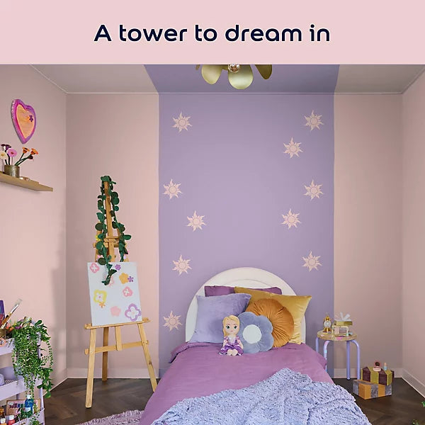 A styled children's bedroom interior with a lavender accent wall decorated with white star decals, a bed with purple bedding and flower-shaped pillows, an easel with artwork, and a pink header at the top reading 'A tower to dream in'.