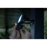 Person attaching a device to a vehicle's window with a blurred outdoor background Brennenstuhl JARO 1060 P LED Spotlight with Motion Detector | 10W | 1150 Lumen | IP65