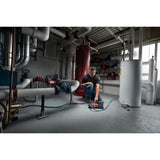 Person working on a piece of equipment in a large industrial setting with pipes and machinery. Milwaukee M18BTP-0 M18 Transfer Pump | Bare Unit