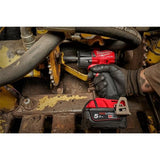 Milwaukee 5V-LITHI+ cordless impact wrench being used by a gloved hand on a rusty piece of industrial machinery.