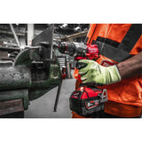 Person using a Milwaukee power drill on a metal object in an industrial setting
