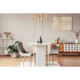Prestige Hoban White
A modern dining room scene featuring a white marble-top dining table with gold metal legs, flanked by two gray upholstered chairs. The room has light beige walls, a gold multi-arm chandelier, a patterned wooden sideboard, and decorative plants.