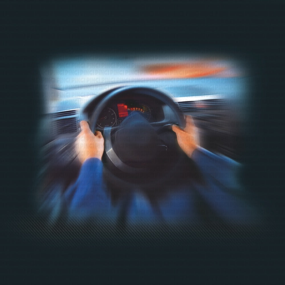 A blurred first-person view of hands holding a steering wheel inside a car, with motion blur and a dark interior background.