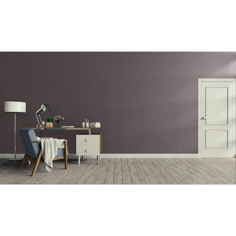A modern interior room scene with a muted purple-gray wall, light wood floor, white door, desk, chair, lamp, and small cabinet.