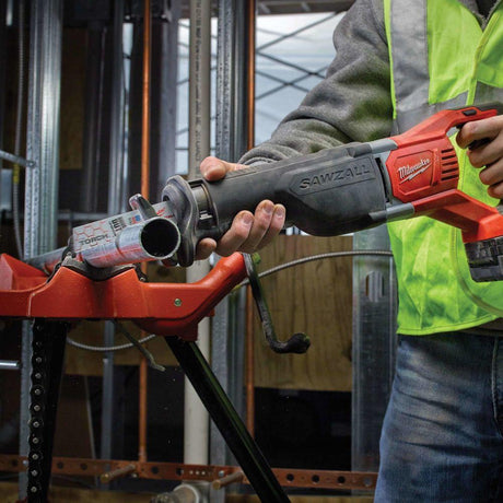 Person using a Milwaukee Sawzall tool in a construction setting