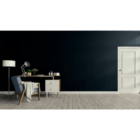 A modern room scene with a dark navy wall, light wood floor, a white door on the right, and a home office setup on the left featuring a desk, lamp, chair, and draped throw blanket.
