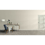 A minimalist interior room with a light beige wall, gray wood floor, a white door on the right, and a home office setup on the left featuring a desk, lamp, chair, and small cabinet.
Prestige Coco Light