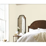 Bedroom with a large mirror on the wall next to a bed. Prestige Coco Pale Paint