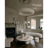 A styled interior room scene showing a curved cream bouclé sofa, matching chair, round coffee table, pendant light, and fireplace. The image includes the Prestige logo and text in the upper right reading 'Prestige Villa Vista' and 'Greene Breeze 28' with 'Prestige-Main Surfact Matt.