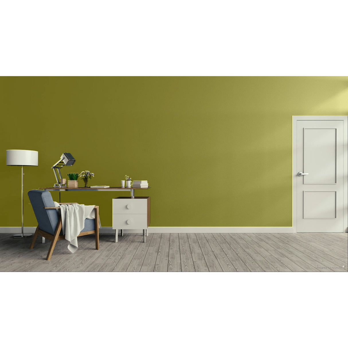 A modern interior room with a large olive green wall, light wood plank floor, a white door on the right, and a home office setup on the left featuring a desk, lamp, chair, and throw blanket.