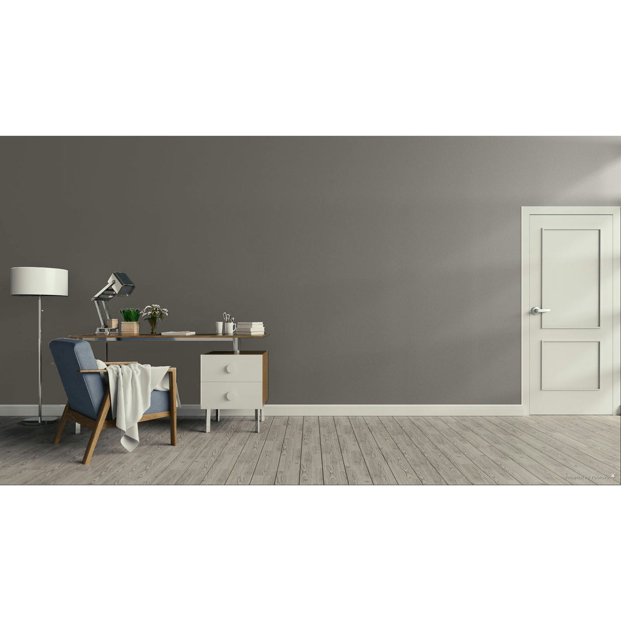 A minimalist room scene with a gray wall, light wood floor, a white door on the right, and a furnished study area on the left featuring a desk, lamp, chair, and draped throw blanket.