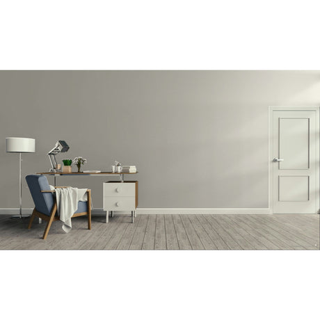 A minimalist room scene with a gray wall, light wood floor, a blue upholstered armchair with a draped throw, a wooden desk with a lamp and small accessories, a white floor lamp, and a white door on the right.
Prestige Letterpress Paint