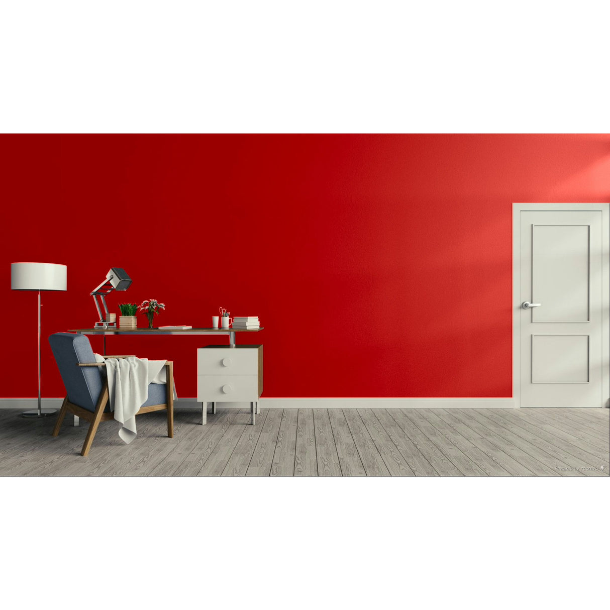 A modern room with a bold red wall, light gray wood flooring, a white door on the right, and a home office setup on the left featuring a desk, lamp, chair, and throw blanket.