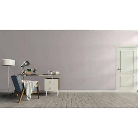 A minimalist room scene with a light gray wall, gray wood floor, a white door on the right, and a home office setup on the left featuring a desk, lamp, chair, and small cabinet.