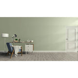 A minimalist room scene with a sage green wall, light wood floor, a white door on the right, and a home office setup on the left featuring a blue armchair, desk, lamp, and small cabinet.
Prestige Monet Paint