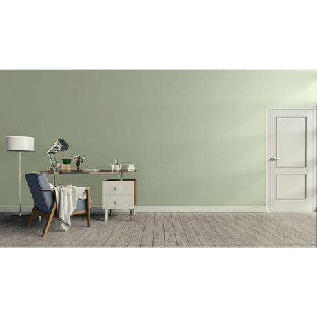 A minimalist room scene with a sage green wall, light wood floor, a white door on the right, and a home office setup on the left featuring a blue armchair, desk, lamp, and small cabinet.
Prestige Monet Paint