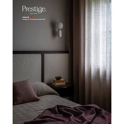 A styled bedroom interior with a bed, textured headboard, bedside table, wall lamp, and sheer curtains. The words 'Prestige Air' and 'Prestige Air-Infusing Scendable Matt' appear in the upper left, suggesting this is a fragrance or home fragrance marketing image rather than a straightforward product photo.
