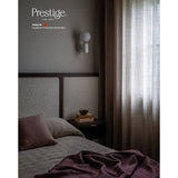 A styled bedroom interior with a bed, textured headboard, bedside table, wall lamp, and sheer curtains. The words 'Prestige Air' and 'Prestige Air-Infusing Scendable Matt' appear in the upper left, suggesting this is a fragrance or home fragrance marketing image rather than a straightforward product photo.