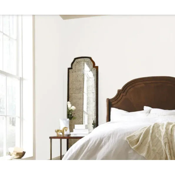 Bedroom with a large mirror on the wall next to a bed with white bedding.
