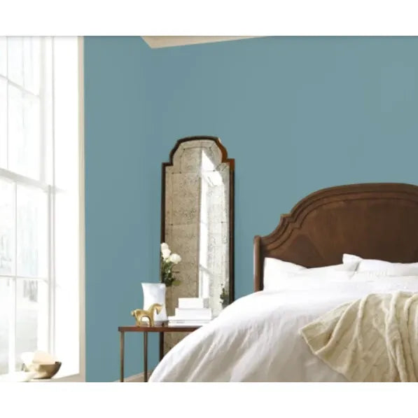 Bedroom with wooden headboard, mirror, and light blue walls.