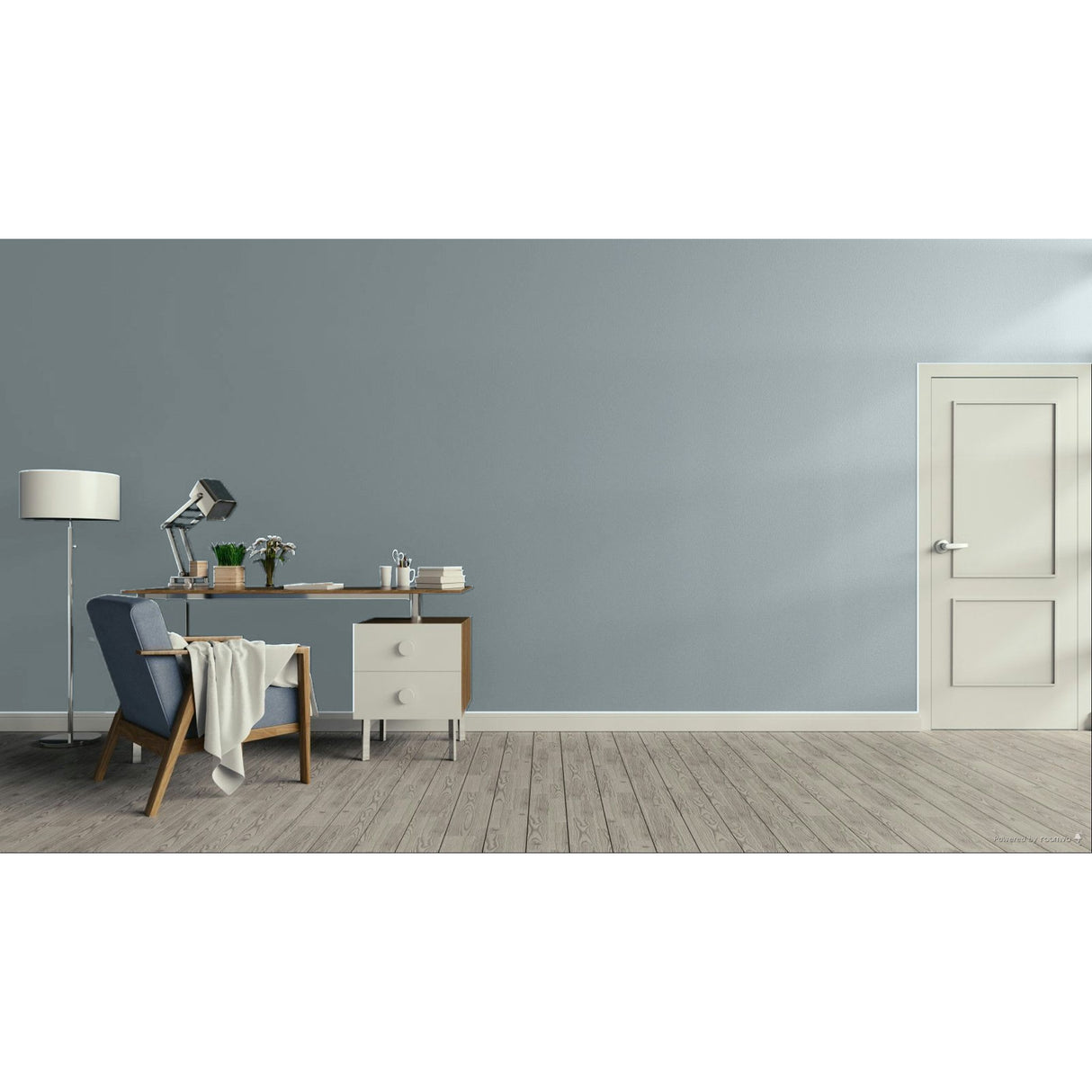 A minimalist room scene with a muted blue-gray wall, light wood floor, a white door on the right, and a furnished study area on the left with a blue armchair, desk, lamp, and small cabinet.