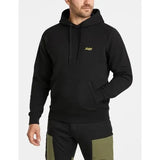 A man wearing a black pullover hoodie with a small yellow 'Lifestyle' logo on the left chest, paired with black and olive green pants, against a light gray background.
