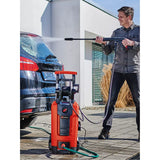 A man is washing a black SUV outdoors using a red and black K&N brand high-pressure water cleaner with a hose on a paved driveway. Einhell Power Tool Classic Pressure Washer 1900W 140 Bar
