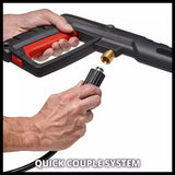 Close-up of a person's hands demonstrating a quick-coupling system on a black and red pressure washer nozzle, with a brass connector visible against a white background.