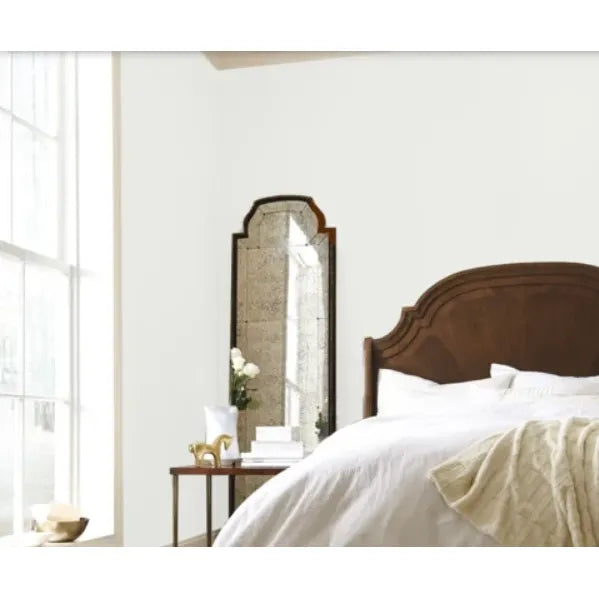 Bedroom with wooden headboard, large mirror, and white bedding.