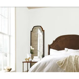 Bedroom with wooden headboard, large mirror, and white bedding.