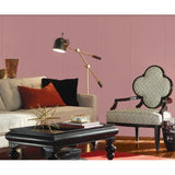 A styled living room scene featuring a pink paneled wall, a cream sofa with red and black pillows, a black coffee table, a gold floor lamp, and a patterned armchair. Prestige Betsy Light Paint