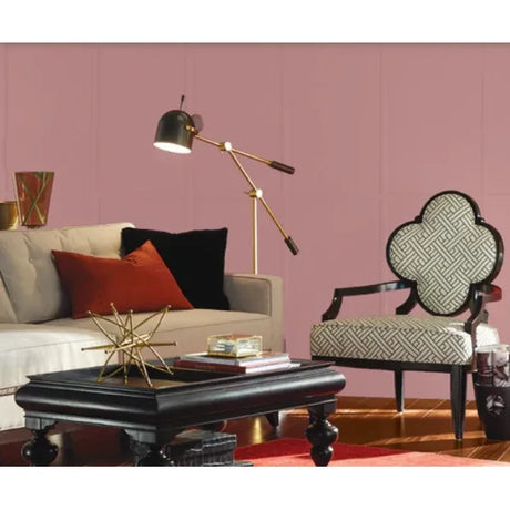 A styled living room scene featuring a pink paneled wall, a cream sofa with red and black pillows, a black coffee table, a gold floor lamp, and a patterned armchair. Prestige Betsy Light Paint