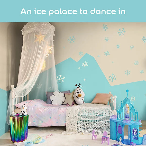 A children's bedroom styled with Frozen theme wall decals, featuring a bed with pink bedding, a white canopy, a blue castle toy, and a mountain-shaped wall decal in light blue and beige.