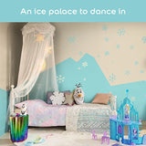 A children's bedroom styled with Frozen theme wall decals, featuring a bed with pink bedding, a white canopy, a blue castle toy, and a mountain-shaped wall decal in light blue and beige.