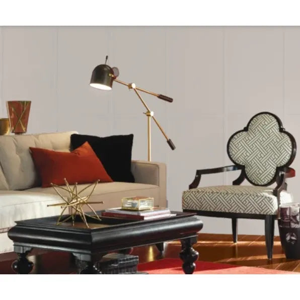 Prestige Hepburn Pale
A styled living room scene featuring a beige sofa with red and black pillows, a black coffee table, a gold floor lamp, and a patterned armchair against a white paneled wall.