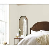 Prestige Hoban White
A tall, full-length floor mirror with an arched top and dark wood frame, styled in a bright bedroom next to a bed with white linens and a wooden headboard.