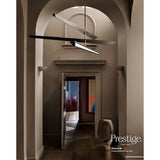 A modern multi-light linear chandelier with three intersecting angled arms, shown hanging in a grand arched hallway. The fixture features a brushed silver metal finish on the upper arms and a black finish on the lower bar, with a warm white light glowing from the central bulb.
Prestige Vincenzo Paint