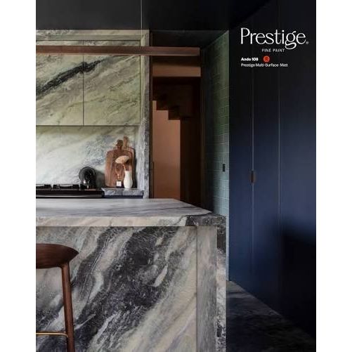 Prestige Ando
A modern kitchen interior featuring a large marble island and matching marble cabinetry in a green, gray, and white veined pattern, alongside dark navy cabinets and a wooden stool. The Prestige Elite Paint brand logo is visible in the top right corner.