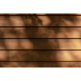 Horizontal wooden planks in warm medium brown tones with soft dappled shadows cast across the surface.
A can of Tikkurila Valtti Plus Color durable wood stain, featuring a label with a wood-grain pattern and a red brand logo block on a white. 
background. Tikkurila Valtti Plus Colour  - Woodstain in Matt Finish