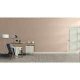 A minimalist interior room scene with a dusty pink wall, gray wood floor, a white door on the right, and a home office setup on the left featuring a desk, lamp, chair, and small cabinet. Prestige Chalking Mid Paint