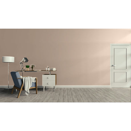 A minimalist interior room scene with a dusty pink wall, gray wood floor, a white door on the right, and a home office setup on the left featuring a desk, lamp, chair, and small cabinet. Prestige Chalking Mid Paint