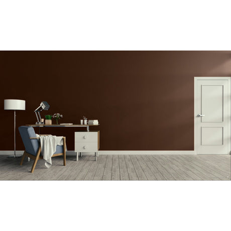 A minimalist room scene with a dark brown wall, light wood floor, a white door on the right, and a home office setup on the left featuring a blue armchair, desk, lamp, and small cabinet.
